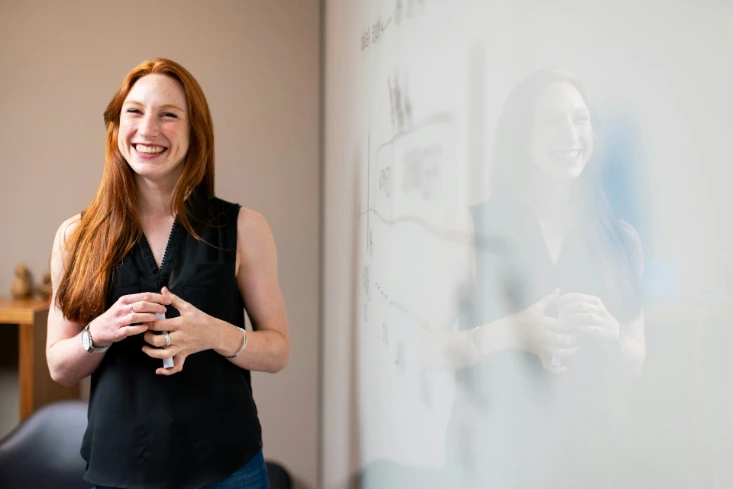 woman in blue tank top standing beside white wall